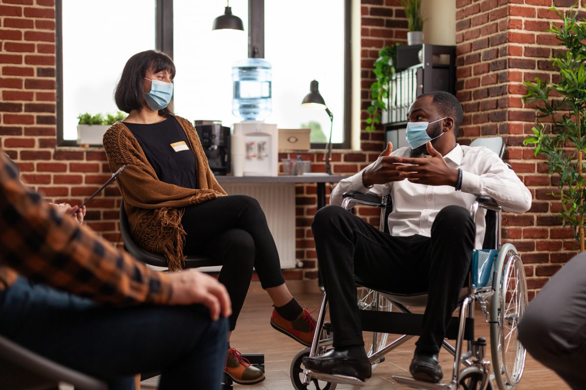 man-with-disability-talking-group-therapy-session-with-people-having-alcohol-addiction-patients-wearing-face-masks-attending-aa-meeting-have-discussion-with-psychologist-1200x800.jpg
